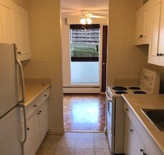 A kitchen with white cabinets and a refrigerator.